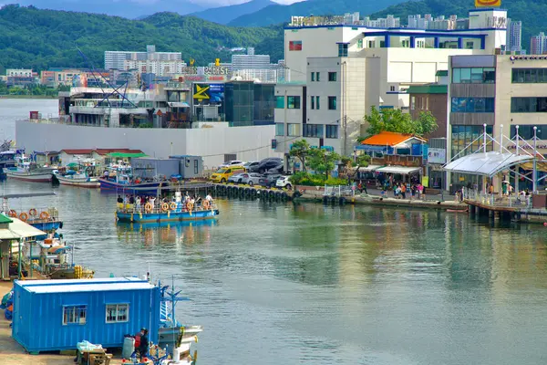 stock image Sokcho, South Korea - July 28th, 2024: Abai Village Ferry glides across the tidal channel in Sokcho, carrying passengers between the bustling waterfront and the historic Abai Village, with fishing boats docked nearby.