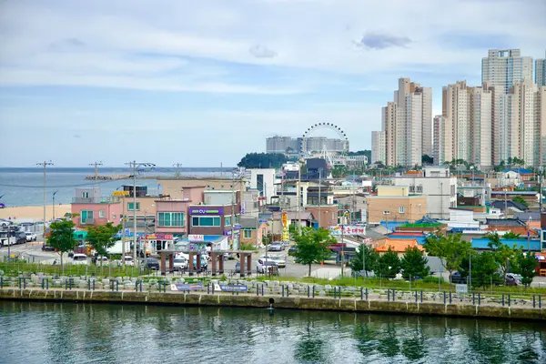 stock image Sokcho, South Korea - July 28th, 2024: A vibrant view looking south from Geumgang Grand Bridge, showcasing Sokcho Beach, the Sokcho Eye Ferris Wheel, and a mix of modern high-rises and colorful local buildings along the coast.