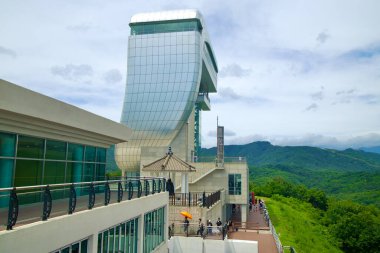 Goseong County, Güney Kore - 28 Temmuz 2024: Modern Birleşme Gözlemevi Kulesi 'nin dış görünüşü, zarif mimarisi ve gözlem güverteleriyle, DMZ yakınlarındaki yemyeşil dağlık araziye tepeden bakan.