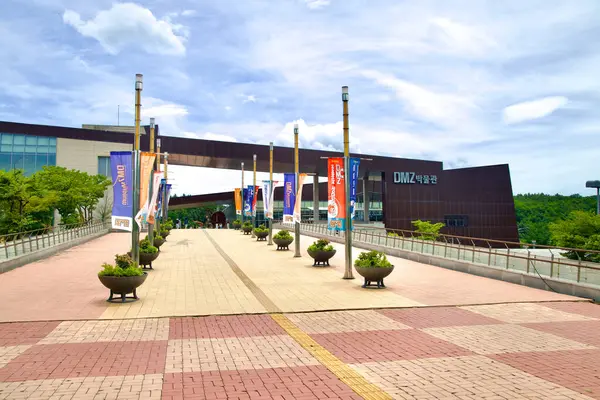 stock image Goseong County, South Korea - July 28th, 2024: The DMZ Museum stands as a modern educational facility, providing historical insights into the Korean Demilitarized Zone, with banners lining the walkway leading to the entrance.