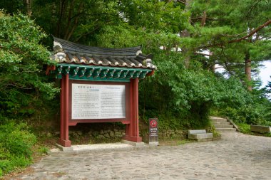 Goseong İlçesi, Güney Kore - 28 Temmuz 2024: Cheonggan Pavyonu 'na kadar uzanan kaldırım taşı yolunda, yemyeşil otlaklarda yuva yapmış ziyaretçilere tarihi ve kültürel bağlam sağlayan bir plaket bulunuyor..