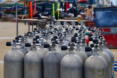 Goseong County, Güney Kore - 28 Temmuz 2024: Scuba tanklarının yakın çekim görüntüsü Gyoam Limanı 'nda kullanıma hazır, arka planda renkli dalış teçhizatı ve ekipmanlarıyla, sualtı maceraları için hazırlıkları gösteriyor.