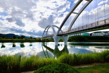 Ulsan, Güney Kore - 9 Temmuz 2019: Simnidaebat Köprüsü sakin Taehwa Nehri üzerinde çarpıcı bir gökyüzü ve durgun suda yansımaları ile modern mimariyi doğanın ortasında sergiliyor..