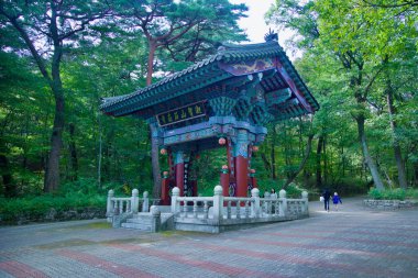 Ulsan, South Korea - October 22nd, 2023: The intricately carved and painted entrance gate to Seoknamsa Temple, surrounded by a lush forest, welcoming visitors into the serene temple grounds. clipart