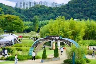 Ulsan, Güney Kore - 5 Ekim 2024: Ziyaretçiler Güney Kore 'nin Ulsan kentindeki Taehwa Nehri Ulusal Bahçesi' ndeki Bambu Ekoloji Parkı 'nı, yemyeşil alanlar ve ağaçların altında sergilenen çeşitli etkinliklerle keşfediyorlar..