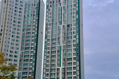 Ulsan, South Korea - October 27, 2024: A moving ladder truck reaches up to the 21st floor of a high-rise apartment complex, assisting movers in transferring belongings through a window. clipart