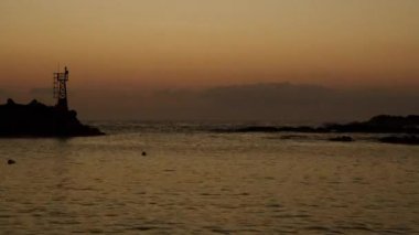 Goseong İlçesi, Güney Kore - 3 Kasım 2024: Huzurlu bir zaman dilimi, Muam Limanı 'ndan bakıldığında Doğu Denizi üzerinde altın gündoğumunu yakalar. Siluetli kaya oluşumları ve sakin sular sakin bir sahne hazırladı..