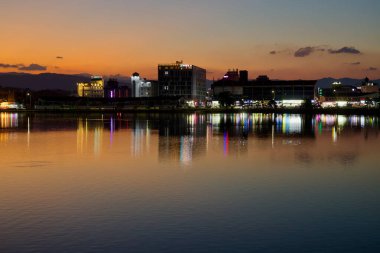 Gangneung, Güney Kore - 3 Kasım 2024: Gün batımında Gyeongpodae Gölü 'nün çarpıcı manzarası sakin suları aydınlatan şehir ışıklarının canlı yansımaları. Güney Kore, Gangneung 'daki huzurlu ve renkli akşam atmosferini yakalıyoruz..