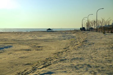 Goseong İlçesi, Güney Kore - 3 Kasım 2024: Bongpo Sahili 'nin geniş ve sakin manzarası alacakaranlıkta denize doğru uzanır, balık tutan insanların siluetleri ve kumlu alanı beneklendiren yalnız bir sığınak.
