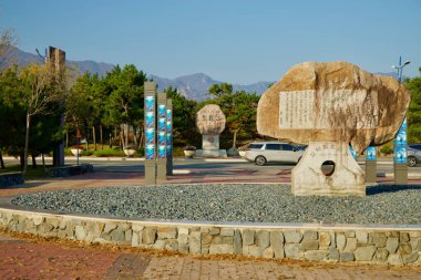 Sokcho, South Korea - November 3rd, 2024: Monumental stones engraved with Korean inscriptions stand at the entrance of Seorak Sunrise Park, surrounded by scenic landscaping and mountain views in the background. clipart