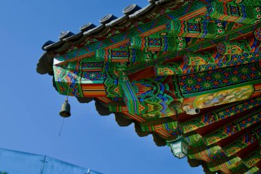 Yangyang İlçesi, Güney Kore - 3 Kasım 2024 Naksansa vitrinindeki geleneksel bir Kore tapınağının süslü ve renkli saçakları açık mavi gökyüzü altında karmaşık işçilik ve canlı dancheong desenleri.