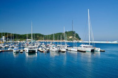 Yangyang İlçesi, Güney Kore - 3 Kasım 2024: Susan Limanı Marina 'da canlı bir sahne, sakin mavi sulara yanaşmış, yemyeşil tepeler ve renkli bir dalgakıran duvar resmiyle çevrili yatlar sergileniyor..