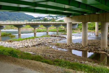 Goesan İlçesi, Güney Kore - 10 Eylül 2020: Seonghwang Nehri 'ni kapsayan ve beton sütunların altında bisiklet süren bisikletçilerin ve suyun aktığı birden fazla köprü manzarası.
