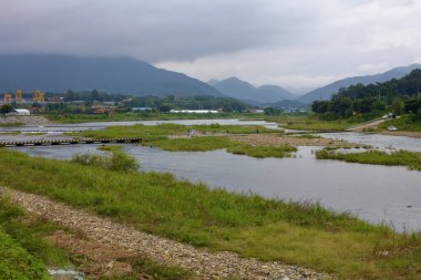 Goesan County, South Korea - September 10, 2020: People explore the shallow waters at the confluence of Ssang Stream and Dal Stream, with a scenic backdrop of distant mountains and rural landscapes. clipart