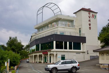 Goesan County, Güney Kore - 10 Eylül 2020: Mannameui Gwangjang binası, bir restoranı ve etkinlik salonu olan yerel bir işletme, kırsal bir yol üzerinde duruyor. Modern tasarımı çevresindeki yeşilliklerle çelişiyor..