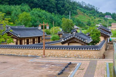 Goesan County, Güney Kore - 10 Eylül 2020 Kore bağımsızlık hareketine bağlı tarihi Joseon döneminden kalma Hong Beom-siks Konutu 'nun kiremitli çatı ve taş duvarları yemyeşil tepelerin zemininde duruyor..