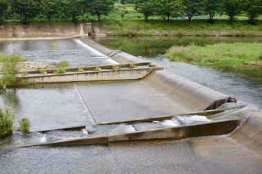 Goesan County, Güney Kore - 9 Eylül 2020: Chilseong Town yakınlarındaki Ssang Stream 'de bulunan beton bir Weir, yemyeşil ve yansıtıcı suların arasında çağlayan bir dizi basamak oluşturarak su akışının düzenlenmesine yardımcı olur..