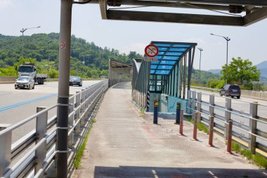 Sejong City, South Korea - May 26, 2021: A pedestrian underpass with a blue canopy runs beneath North Star Road, providing access to the solar-covered bicycle path while ensuring safe crossing for pedestrians and cyclists. clipart