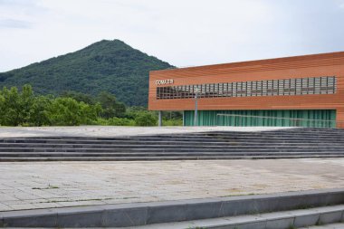 The GOMA Museum, a modern cultural space with a sleek wooden faade, stands against the backdrop of lush green mountains, offering art and exhibitions in a scenic setting. clipart