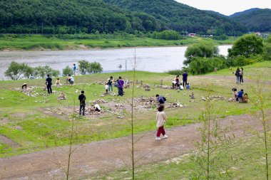 Tarihi Seokjangni Müzesi 'nde Geum Nehri yakınlarında Koreas Paleolitik Mirasını kutlayan taş yığınları inşa eden ziyaretçilerin manzarası.