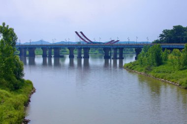 Buyeo İlçesi, Güney Kore - 27 Mayıs 2021: Bekçe Köprüsü Geum Nehri boyunca uzanır ve suyun üzerinde kendine özgü kırmızı ve mavi heykel benzeri yapısı yükselir. Köprü hem araçlara hem de yayalara hizmet ederek manzaralı manzaralar sunuyor. 
