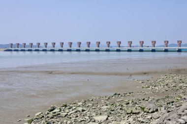 Gunsan, Güney Kore - 28 Mayıs 2021: Su üzerinde uzanan Geum Nehri Estuary Bank manzarası, açık nehir yatağı ve dağılmış kayalar berrak bir gökyüzü altında görülebilir.