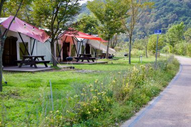 Imsil County, Güney Kore - 4 Ekim 2021: Seomjingang Bisiklet Yolu üzerinde piknik masaları ve barbekü ızgaraları olan bir dizi glamping çadırı nehir kenarında manzaralı ve rahat bir kamp deneyimi sunuyor.