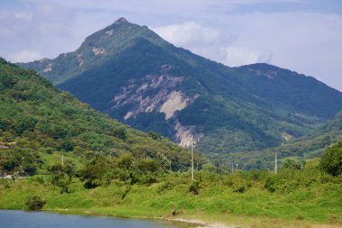 Sunchang İlçesi, Güney Kore - 4 Ekim 2021 Seomjin Nehri boyunca yemyeşil bir dağ zirvesi yükseliyor, yoğun orman yamaçlarına zıt düşen kayalıklarla kaplı..