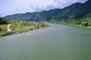 Sunchang County, Güney Kore - 3 Ekim 2021: Seomjin Nehri, Seomjingang Bisiklet Yolu boyunca bisiklet sürücüleri ve doğa meraklıları için manzaralı ve sakin bir manzara sunan dolambaçlı toprak patikaların yanında akar..