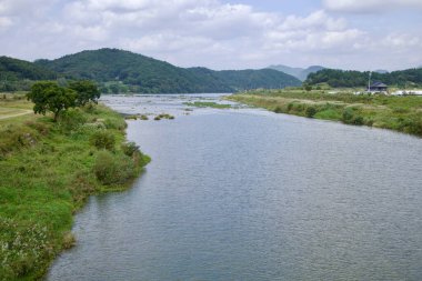 Sunchang İlçesi, Güney Kore - 4 Ekim 2021: Seomjin Nehri, dalgalı tepeler ve kıyıları boyunca dağınık çiftliklerle yemyeşil bir çevre boyunca yavaşça akar ve huzurlu ve manzaralı bir kırsal alan yaratır..