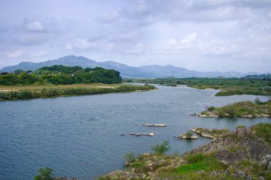 Seomjin Nehri 'nin geniş bir manzarası yemyeşil, dağınık kayalar ve bulutlu gökyüzünün altında uzak dağlar, Kore' nin doğal güzelliğini gözler önüne seriyor..