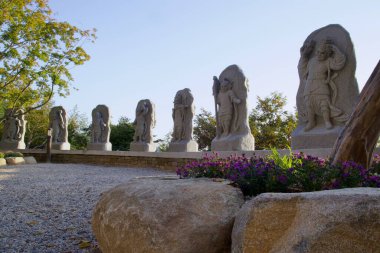 Gurye İlçesi, Güney Kore - 3 Ekim 2021 Saseongam Hermitage tapınağı boyunca uzanan ve batan güneşin sıcacık parıltısıyla yıkanan bir dizi karışık oyulmuş koruyucu heykel..