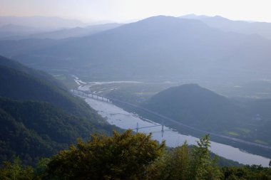 Gurye İlçesi, Güney Kore - 3 Ekim 2021: Saseongam Hermitage 'ın yüksek noktasından görülen dağlık araziyi birbirine bağlayan köprülerle vadiyi saran Seomjin Nehri' nin panoramik görüntüsü.