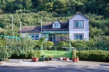 A cozy rural home surrounded by a lush garden and fruit orchards, blending modern and traditional countryside living in a peaceful natural setting. clipart