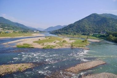Namdo Köprüsü 'nden Seomjin Nehri' nin panoramik görüntüsü ufukta akan sular, çakıl taşları ve yemyeşil dağların uzandığını gösteriyor..