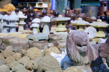 Gwangyang, Güney Kore - 3 Ekim 2021: Kaplumbağalar, fenerler ve aslan oymacılığı içeren el yapımı taş heykellerin bir koleksiyonu, Seomjingang Bisiklet Yolu yakınlarındaki bir yol kenarı pazarında geleneksel Kore toprak kapları ile birlikte sergilenmektedir..