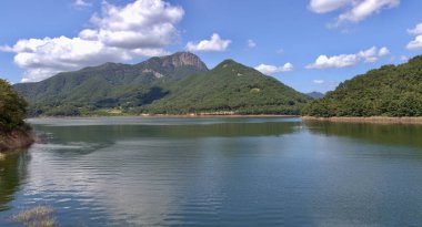 Damyang İlçesi, Güney Kore - 23 Eylül 2020 Damyang Gölü 'nün sakin suları gölün çevresini çevreleyen yemyeşil dağları yansıtıyor, parlak mavi gökyüzünün altında sakin ve pitoresk bir manzara yaratıyor..