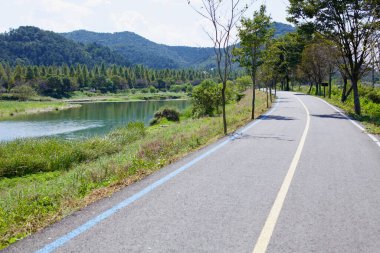 Damyang County, Güney Kore - 24 Eylül 2020 Yeongsan Nehri 'nin yanında yemyeşil ve yuvarlanan tepeler boyunca uzanan düz ve asfalt bir bisiklet yolu. Yeongsangang Bisiklet Yolu ağının bir parçası.