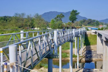 Naju Şehri, Güney Kore - 24 Eylül 2020: Bir bisikletçi, Yeongsangang Bisiklet Yolu 'ndaki küçük bir dereye yayılan yüksek yaya ve bisiklet köprüsü boyunca ilerliyor..