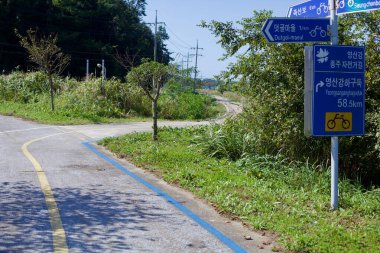Naju Şehri, Güney Kore - 24 Eylül 2020: Yeongsangang Bisiklet Yolu boyunca bir kavşak Dutgol-Maeul ve Yeongsanganghaguduk 'a olan uzaklıkları gösteren mavi bisiklet yolu işaretleri içerir..