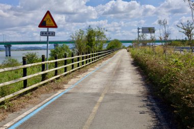 Muan County, Güney Kore - 25 Eylül 2020: Bisiklet uyarı levhası bisikletçileri, Yeongsangang Bisiklet Yolu boyunca Yeongsan Nehri 'ne paralel giden ve uzaktan görülebilen bir köprüyle ilgili uyarıda bulundu.