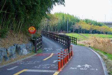 Ulsan City, Güney Kore - 31 Mart 2025: Bir bisiklet ve yaya yolu Taehwa Nehri boyunca Simnidae Ormanı yakınlarında ikiye ayrıldı ve bisikletçileri bu ortak bölgede yavaşlamaya teşvik eden bir işaret var..