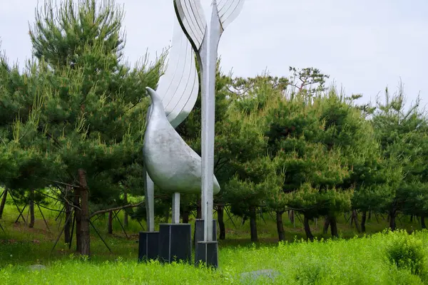 Incheon, Güney Kore - 19 Mayıs 2025: Soyut bir kuş heykeli Ara Waterway boyunca uzanan heykel parkındaki çam ağaçları ve bahar otları arasında yükselir ve modern biçimi doğal çevreyle harmanlar..