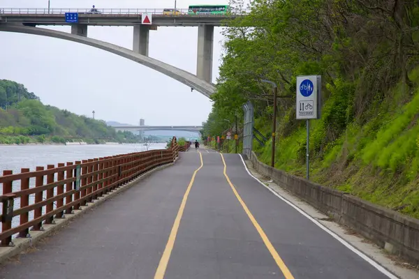 Incheon, Güney Kore - 19 Mayıs 2025: Bisikletçiler, Moksang Köprüsü 'nün altındaki Ara Bisiklet Yolu' nu belirlenmiş işaret ve çitle Gyeongin Ara Su Yolu boyunca yeşil kanal kenarındaki patikayı takip ediyorlar..