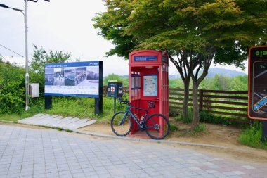 Incheon, Güney Kore - 19 Mayıs 2025: Ara Hangang Kilit Sertifika Merkezi, bisiklet yolundaki bir ağacın altında duruyor, bisikletçiler yolculuklarına devam etmeden önce bisiklet pasaportlarını damgalayabiliyorlar..