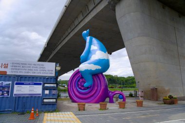 Incheon, Güney Kore - 19 Mayıs 2025: Sicheon Waterside Park 'ta Sicheon Köprüsü' nün altında oturan Bisikletli Bulut Adam olarak bilinen tuhaf bir heykel, şehir altyapısını Ara Waterway 'in yanındaki kamu sanatı ile harmanlıyor..