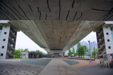 Incheon, Güney Kore - 19 Mayıs 2025: Baekseok Köprüsü 'nün altı, Ara Waterway' in bu kablo geriliminin altında yer alan geniş bir plaza ve modern yapılarla beton yüzeyi boyunca cesur soyut çizgileri ortaya koyuyor..