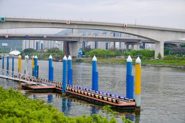 Incheon, Güney Kore - 19 Mayıs 2025: Sicheon Waterside Parkı ve köprü boyunca uzanan yüksek binalar ile Ara Kanalı 'nı çevreleyen renkli bir rıhtım..