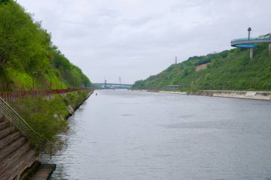 Incheon, Güney Kore - 19 Mayıs 2025: Yeşil yamaçlar ve yaya yolları ile çevrili Gyeongin Ara Waterway geniş bir görünüm, dairesel Ara Gözlemevi kanalı boyunca uzanan uzak köprüler.