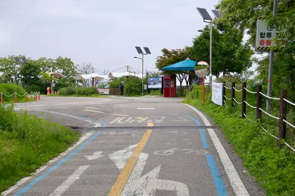 Incheon, Güney Kore - 19 Mayıs 2025: Bisikletçiler Ara Hangang Kilit Sertifika Merkezi 'ne açıkça belirtilmiş bir yol boyunca yaklaşıyorlar, Ara Kanalı ve Han Nehri arasındaki bu kavşakta güneş ışığı ve aynaların altından geçerek.